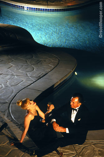 Photo of couple in evening dress by pool at night