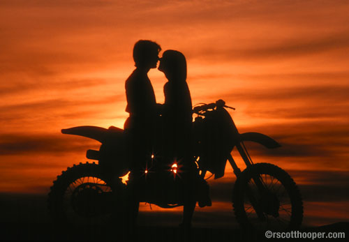 Photo of couple with motorcycle in silhouette at sunset