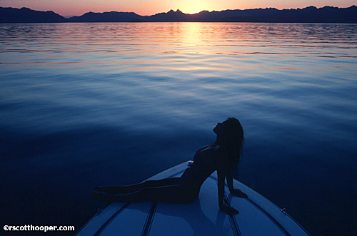 Image of girl in swimsuit on front of boat at sunset