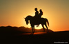 Photo of couple on horse in the sunset